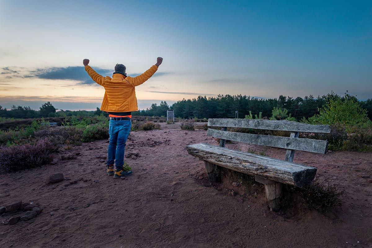 man outdoors with hands raised, symbolizing the celebration of life or victory